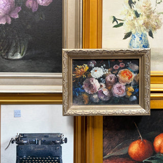 Collection of framed artworks including floral still lifes and a typewriter on a white surface.